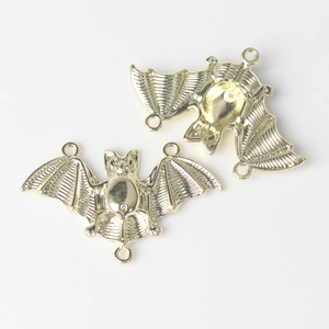 Detailed view of golden bat-shaped alloy connectors with three loops for DIY jewelry