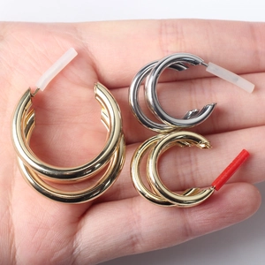 Orecchini a cerchio minimalisti in oro e argento mostrati su un palmo per le dimensioni