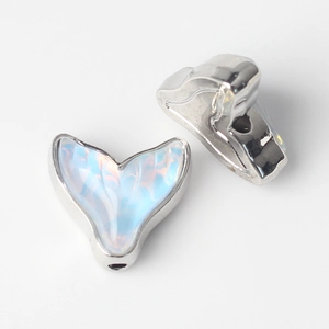 Macro detail of silver fish tail charms with blue resin opal inlay for DIY jewelry