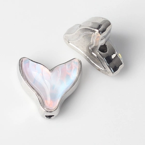 Macro detail of silver fish tail charms with iridescent resin inlay and side holes for DIY