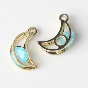 Macro detail of moon-shaped alloy pendants with light blue zircon and golden plating