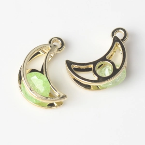 Macro shot of gold crescent moon pendants with green faceted stones for DIY jewelry making
