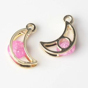 Macro shot of gold moon pendants with glittery pink stone inlay for jewelry DIY