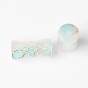 Macro view of saddle ear plugs with blue and orange marble texture on white background