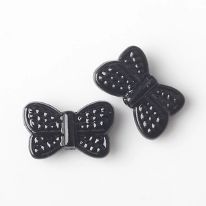 Macro detail of glossy black butterfly beads with textured wings for DIY jewelry
