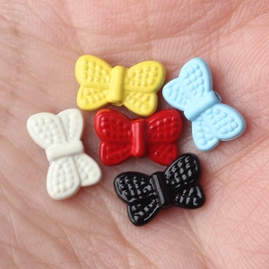 Colorful alloy bow beads for DIY jewelry making held in hand for scale and detail
