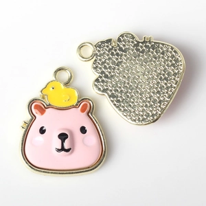 Detail of pink bear charm with yellow duck and star textured gold metal back