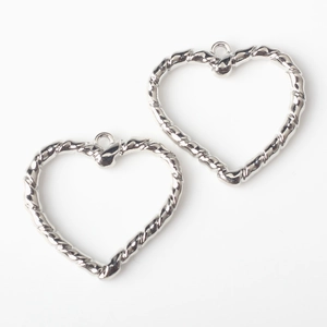 Primer plano de dijes de corazón plateados con textura espiral para joyería DIY