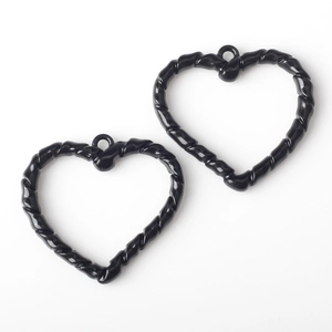Primer plano de dijes de corazón en esmalte negro con bordes de cuerda para joyería