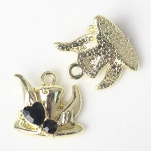 Detail of gold charms with black heart stones and star texture for jewelry making