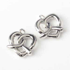 Detalle de dos colgantes plateados en forma de pretzel para creación de joyas DIY