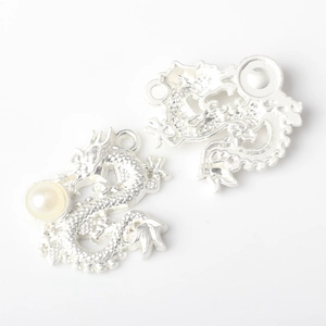 Macro detail of silver dragon pendants with pearl inlay for DIY jewelry making