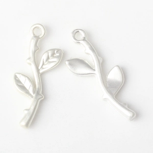 Detail of matte silver branch leaf charms with intricate texture for DIY jewelry making