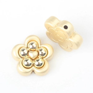 Macro detail of gold flower alloy beads with heart motif and side holes for DIY jewelry