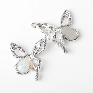Macro detail of silver butterfly charms with opal stones and liquid metal wing design