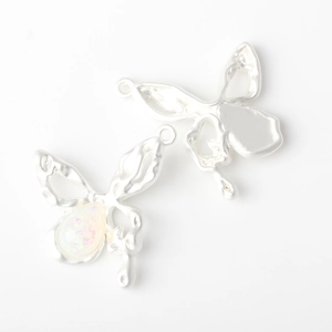 Macro view of matte silver alloy butterfly charms with iridescent stones for DIY jewelry