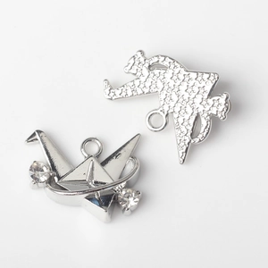 Macro view of silver alloy paper crane and cat pendants with sparkling rhinestones for DIY