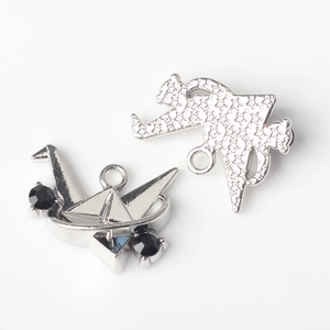 Macro detail of silver paper crane and star-patterned alloy charms for DIY jewelry making
