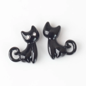 Détail de breloques chat noir poli avec yeux en strass étincelants et queue en spirale