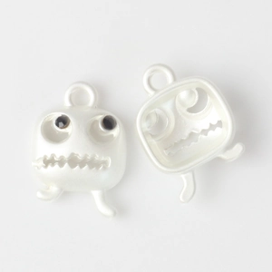 Detailed view of matte white ghost pendants with black bead eyes for DIY jewelry making