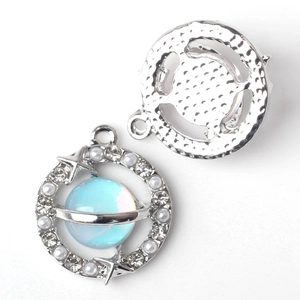 Macro detail of alloy planet pendant showing sparkling zircons and blue orb