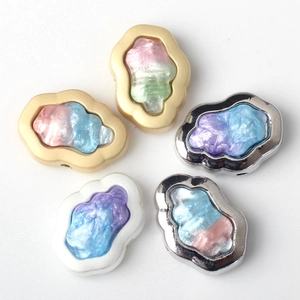 Close-up of cloud-shaped resin charms with iridescent finish and metal frames for DIY crafts