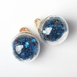 Macro detail of clear glass ball pendant filled with shimmering blue star sequins