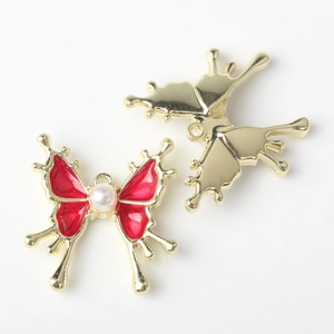Vista macro de colgantes de mariposa dorados con esmalte rojo y detalles de perla blanca