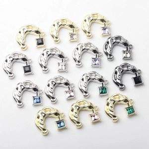 Detailed view of C-shaped metal pendants with lava texture and colored zircon stones