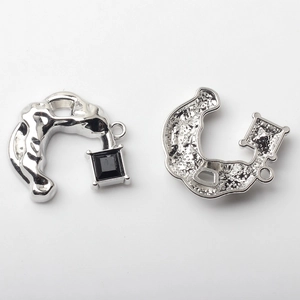 Macro view of C-shaped alloy charm with black gemstone and textured metal finish