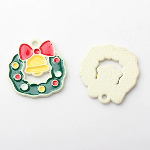 Macro view of colorful enamel Christmas wreath pendants with gold bells for DIY jewelry