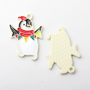 Detail eines bunten Pinguin-Weihnachtsanhängers mit rotem Hut und Metallrückseite