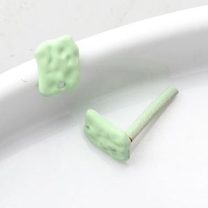 Macro shot of mint green geometric earrings with matte biscuit texture and silver pins