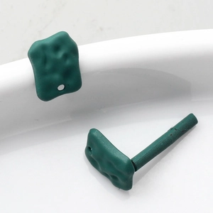 Macro view of matte dark green geometric DIY jewelry charms with hammered rock texture