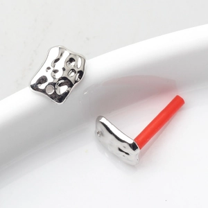 Detail of irregular geometric silver stud earrings with a unique hammered lava texture