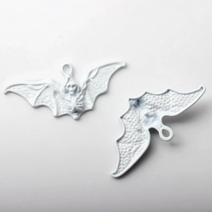 Detailed view of white bat charms with skeleton textures for Halloween jewelry making