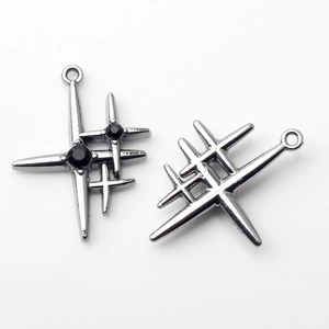 Macro shot of silver cross star charms with black gemstones and integrated hanging loops