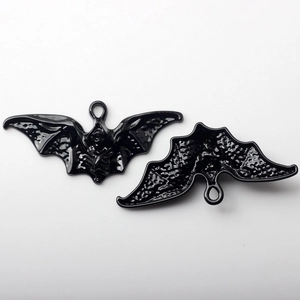Detail of bat-shaped enamel charms with skull engraving and integrated hanging loop