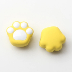 Detailed macro view of yellow alloy cat paw beads with cute white enamel pads for DIY jewelry