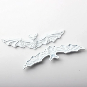 Detailed macro view of white bat alloy pendants featuring embossed wing textures and holes