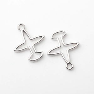 Detalle macro de dijes de avión plateados con diseño hueco para creación de joyas
