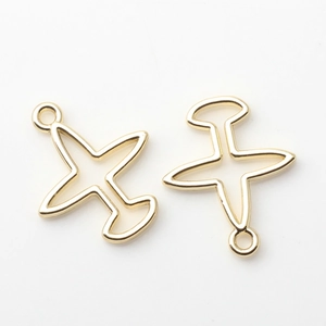 Detalle macro de colgantes de avión dorados huecos con lazos para creación de joyas