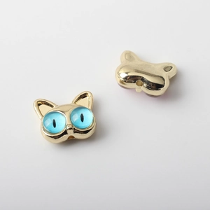 Detalle de dijes de gato dorados con piedras de ojo de gato azul y agujeros para joyas DIY