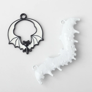 Macro detail of black and white bat charms for DIY jewelry making with top hanging holes