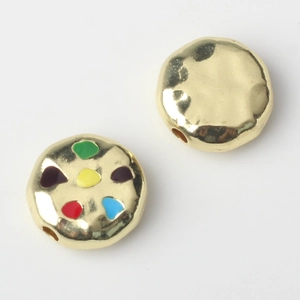 Close-up of golden alloy beads with colorful enamel dots for DIY jewelry making