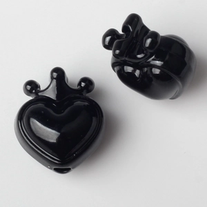 Macro detail of black heart pendants with crown accents for DIY jewelry making