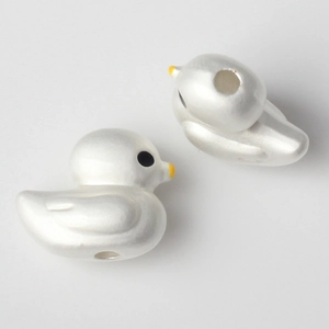 Macro detail of bird-shaped beads with pearlescent finish and center hole for DIY jewelry