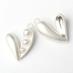 Macro detail of heart-shaped pearl pendant with matte silver alloy frame for DIY jewelry