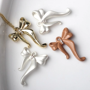 Detalle de colgantes de lazo con pedrería para joyería DIY en oro, plata y marrón