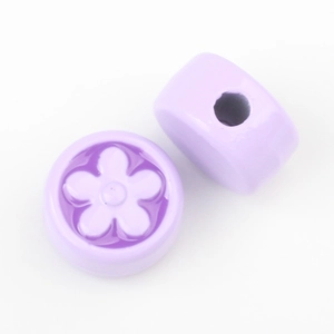 Macro shot of lavender round beads with floral 3D pattern and central hole for DIY jewelry